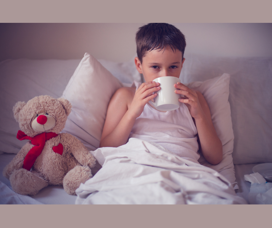Nemocné dítě v posteli s medvídkem pije čaj